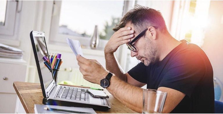 Frustrated man at table with computer