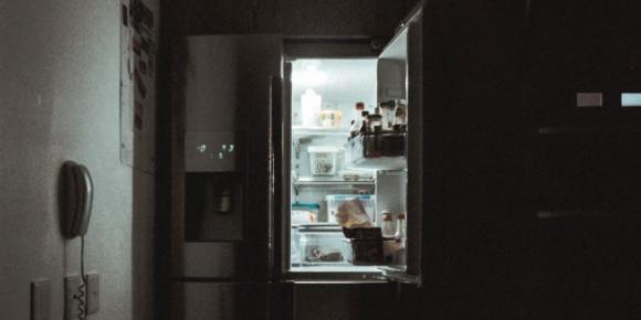 Refrigerator with door open in dark kitchen