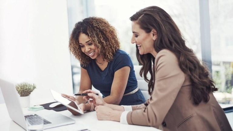 Two women smiling looking at tablet